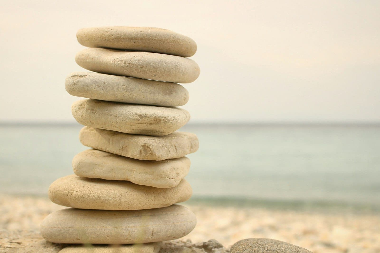 A balanced stack of smooth beach stones by the sea — the Complete Glow Protocol pairs Methylene Blue topicals with Infrared therapy